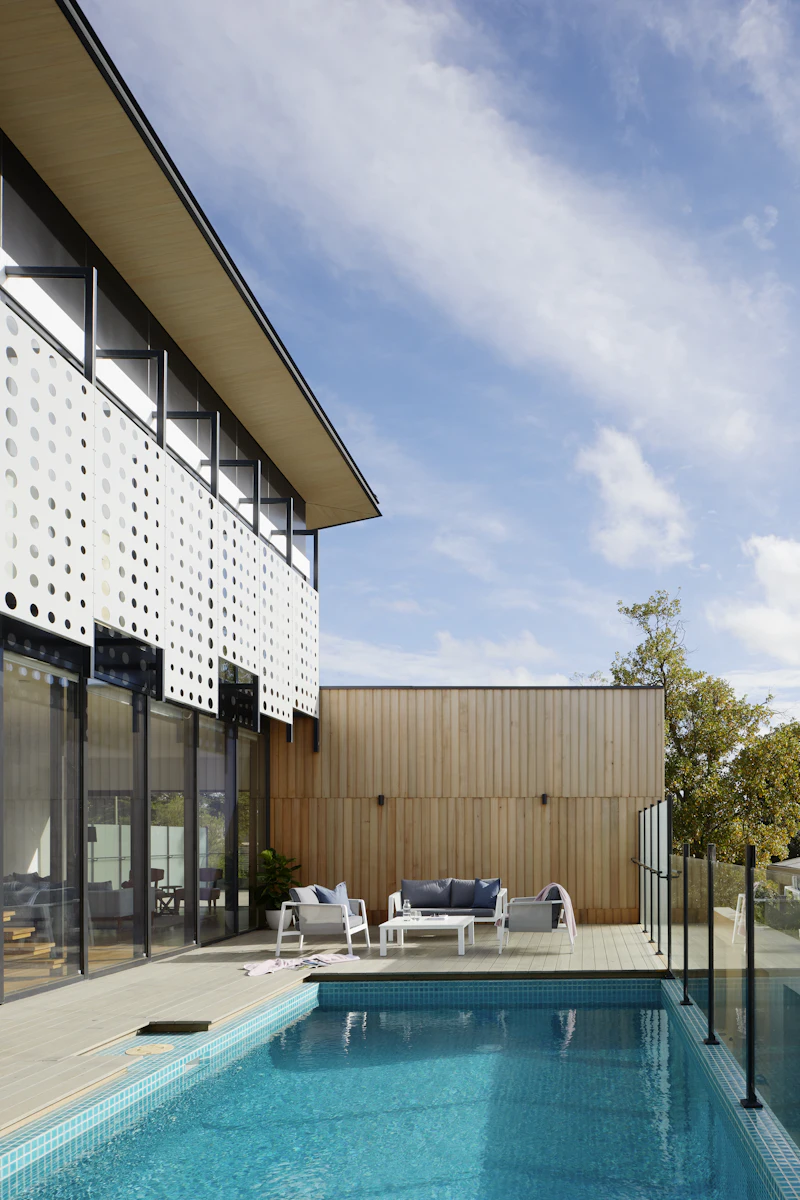 Pooldeck aus Thermoholz mit Lounge-Bereich vor heller Holzfassade
